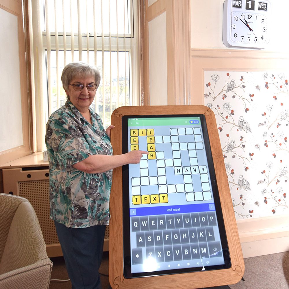 Elderly woman doing a crossword on an interactive activity screen